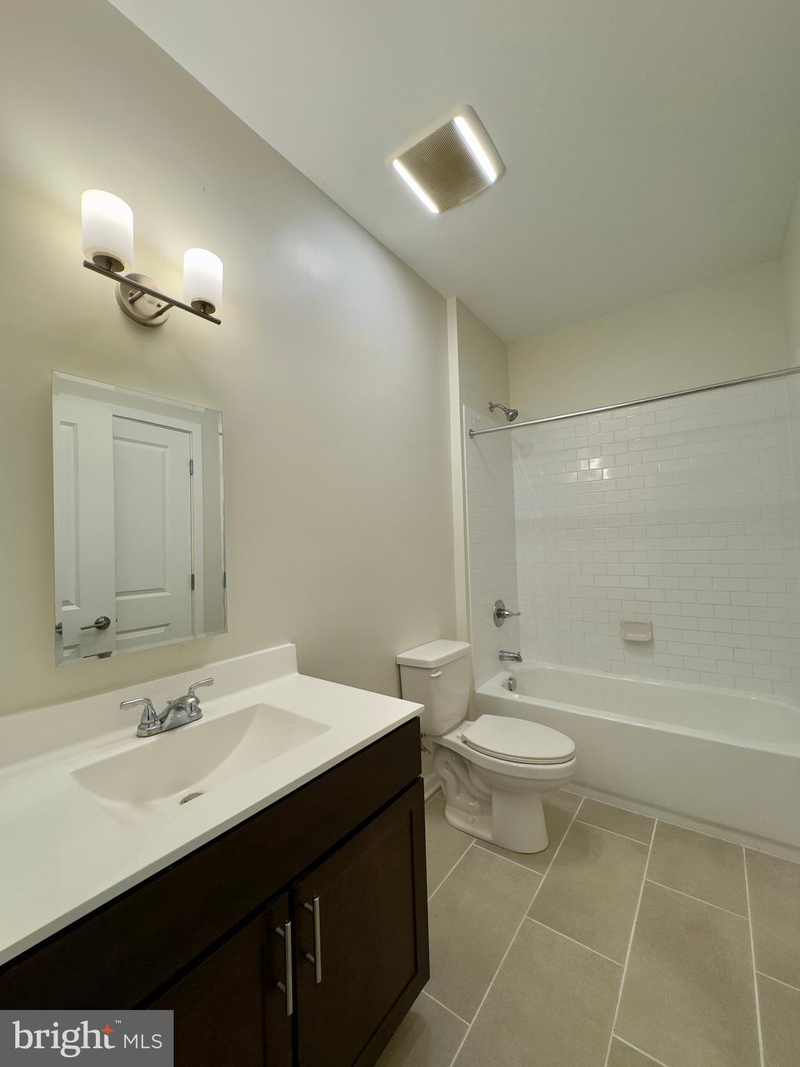 4909 Hamilton Avenue, Unit 4909B Baltimore, MD 21206 - Photo 12 of 15 a bathroom with a bathtub shower sink vanity and toilet