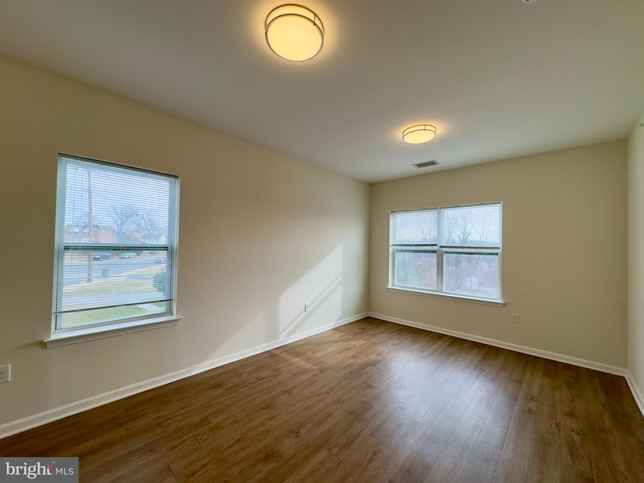 4909 Hamilton Avenue, Unit 4909B Baltimore, MD 21206 - Photo 3 of 15 an empty room with wooden floor and windows