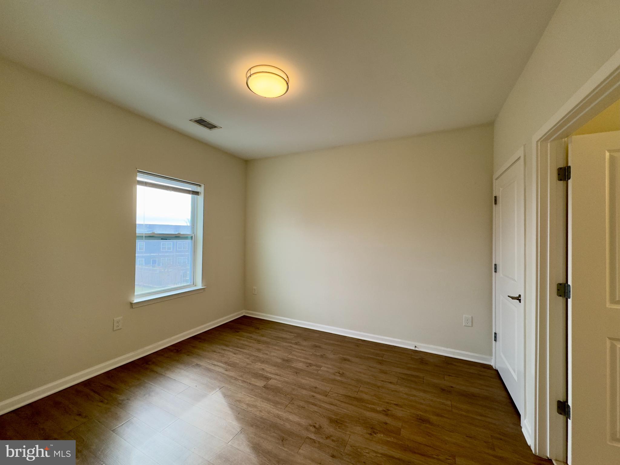 4909 Hamilton Avenue, Unit 4909B Baltimore, MD 21206 - Photo 4 of 15 an empty room with wooden floor and windows