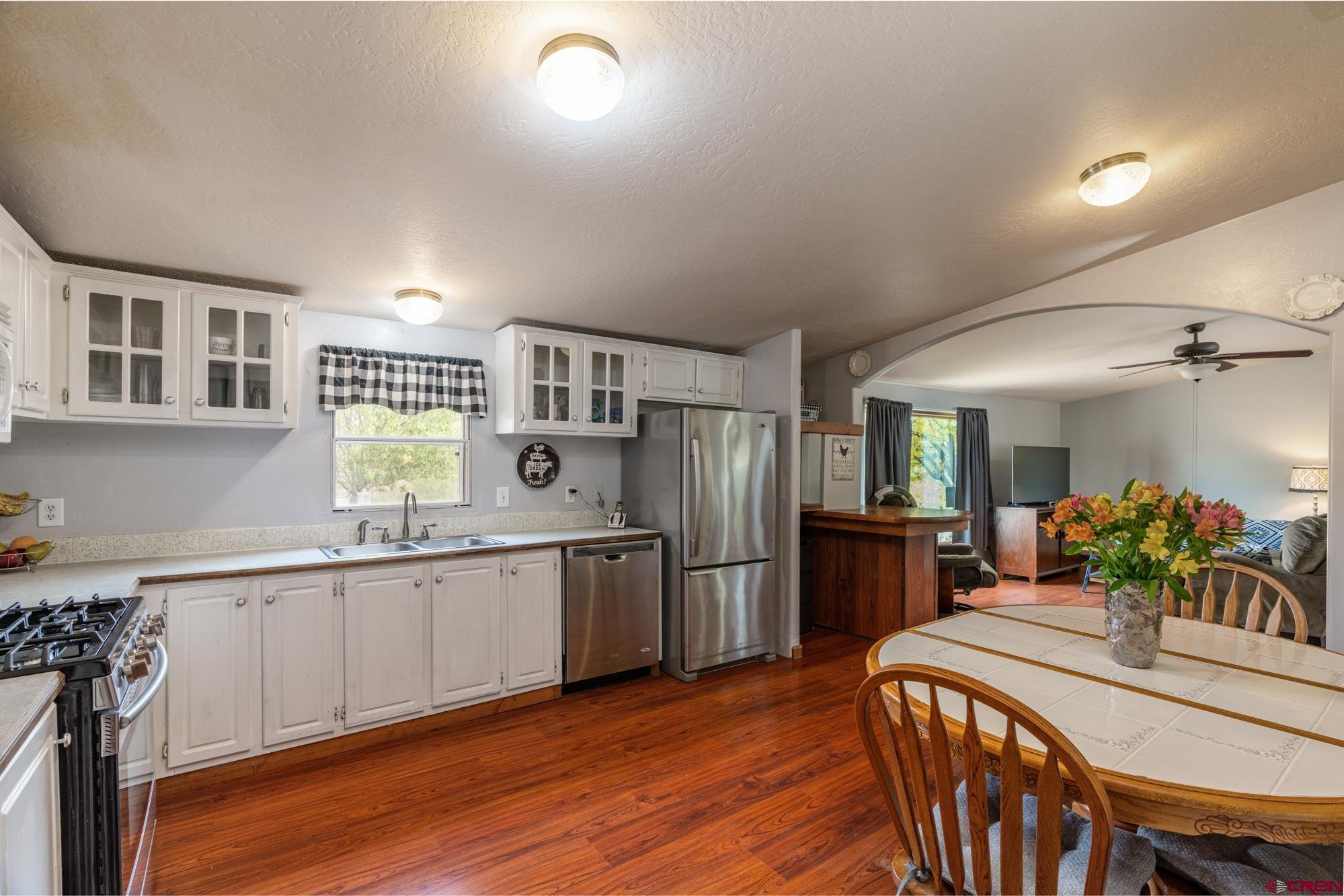 25109 Rd L.4 Cortez, CO 81321 - Photo 11 of 33 a kitchen with stainless steel appliances granite countertop a kitchen island hardwood floor sink stove dining table and chairs