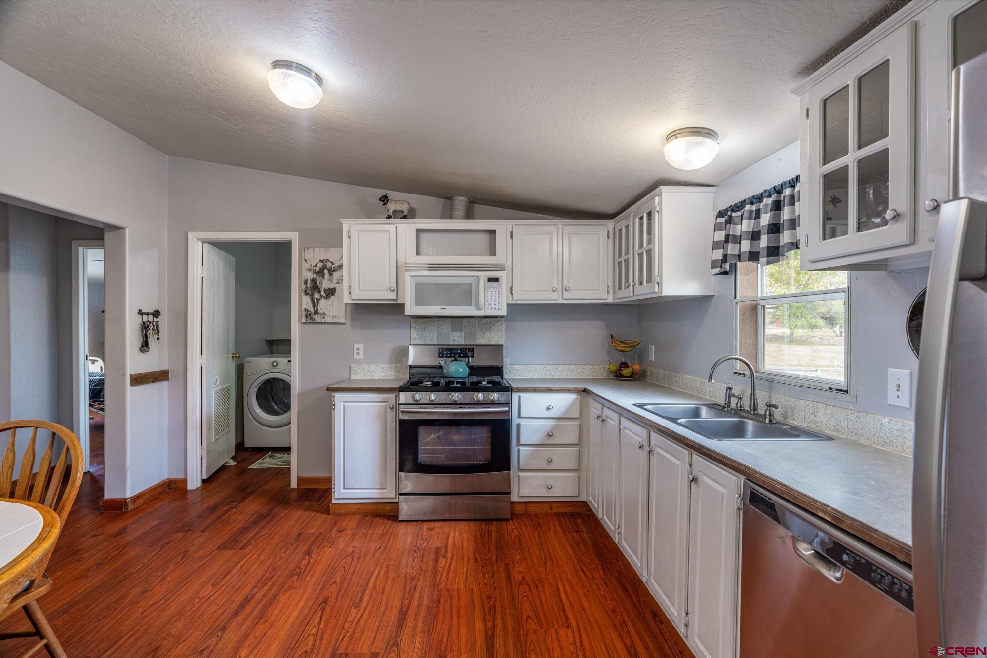 25109 Rd L.4 Cortez, CO 81321 - Photo 13 of 33 a kitchen with stainless steel appliances granite countertop a refrigerator a sink dishwasher a stove and white countertops with wooden floor