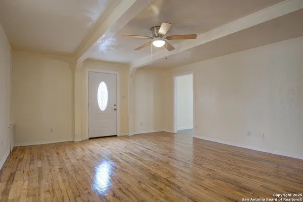 an empty room with wooden floor and windows