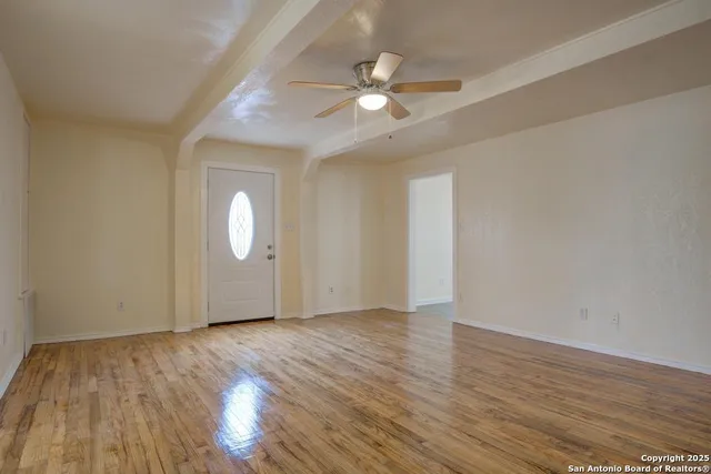 an empty room with wooden floor and windows