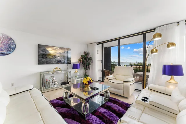 a living room with furniture a flat screen tv and a floor to ceiling window