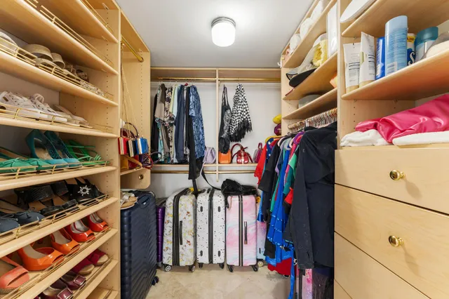 a view of walk in closet with clothes and shoes