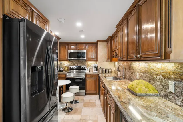 a kitchen with stainless steel appliances granite countertop a refrigerator and a sink