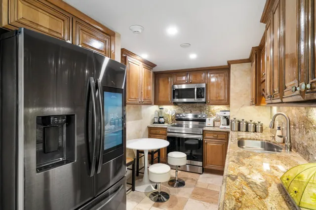 a kitchen with stainless steel appliances a refrigerator a stove a sink dishwasher a dining table and chairs with wooden floor