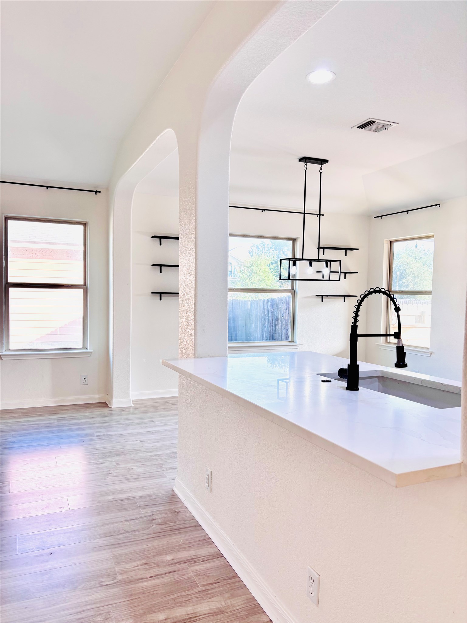 606 Old Peak Road Georgetown, TX 78626 - Photo 11 of 23 An inviting kitchen island anchors a room with light wood-look flooring and graceful arched doorways.