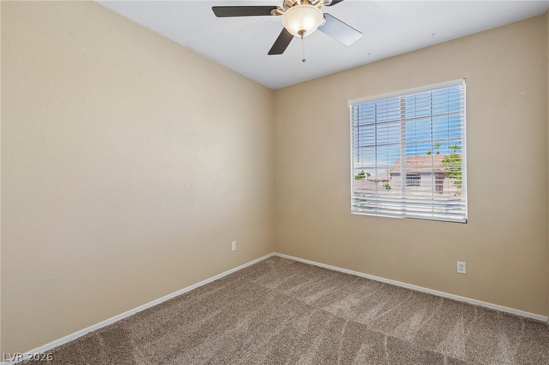 1727 Millstream Way Henderson, NV 89074 - Photo 38 of 46 A well-lit bedroom features plush carpeting and a ceiling fan, offering a comfortable personal retreat.