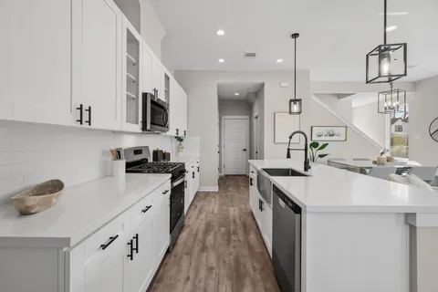 a large kitchen with lots of counter space a sink appliances and living room view