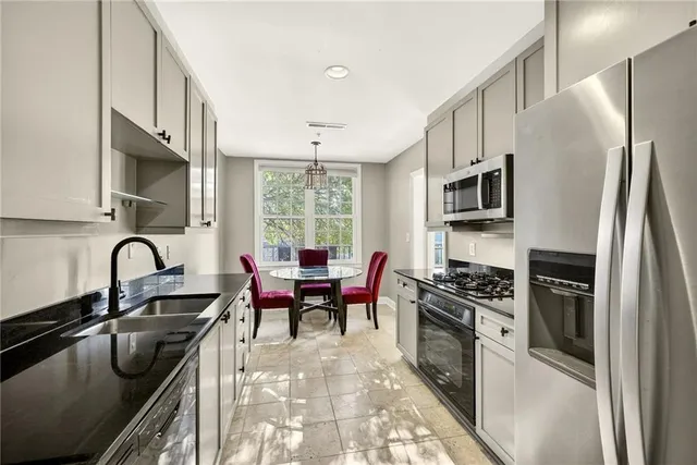 a kitchen with stainless steel appliances granite countertop a sink a stove a refrigerator cabinets and a dining table