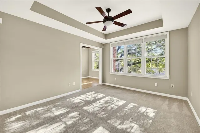 an empty room with windows and ceiling fan