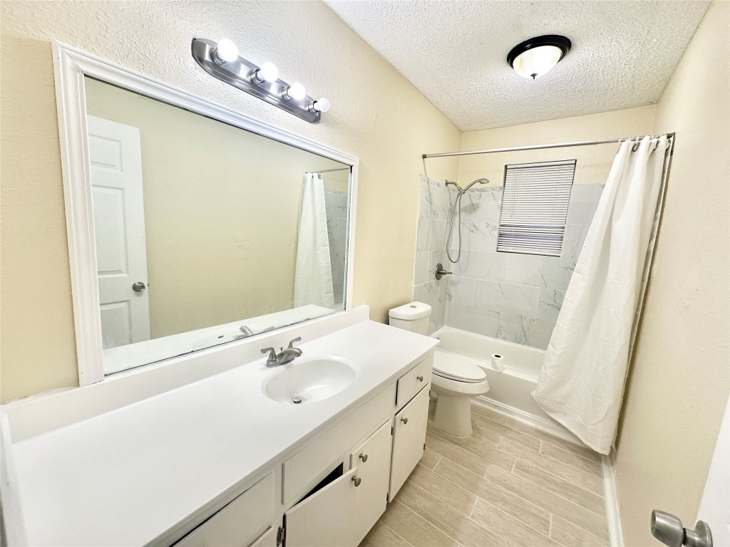 4302 Scottsdale Road, Unit B Austin, TX 78721 - Photo 16 of 37 Full bath featuring vanity, shower / tub combo with curtain, a textured ceiling, and wood tiled floors