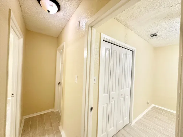 a view of an empty room with wooden floor and a ceiling fan