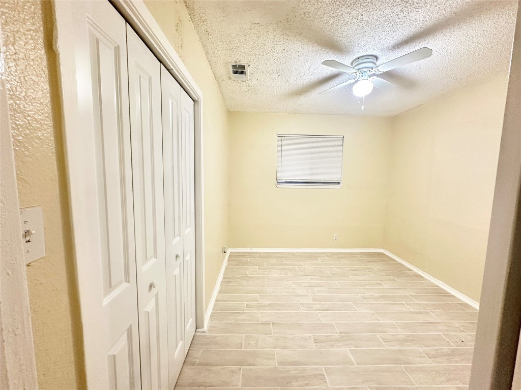 4302 Scottsdale Road, Unit B Austin, TX 78721 - Photo 21 of 37 Unfurnished bedroom featuring a closet, a textured ceiling, wood finish floors, and a ceiling fan