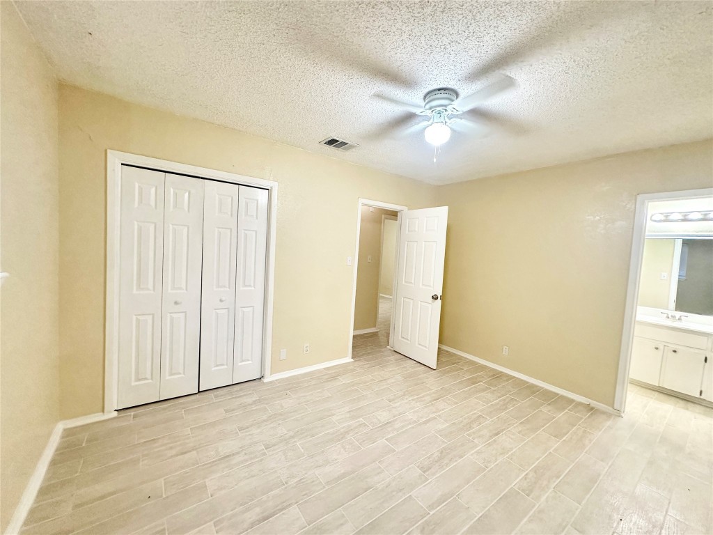 4302 Scottsdale Road, Unit B Austin, TX 78721 - Photo 25 of 37 Unfurnished bedroom with ceiling fan, a closet, wood finish floors, and a textured ceiling