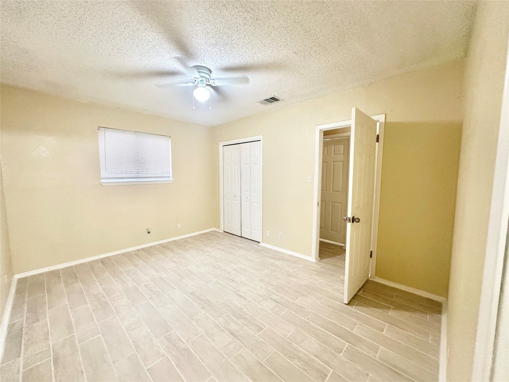 4302 Scottsdale Road, Unit B Austin, TX 78721 - Photo 30 of 37 Unfurnished bedroom featuring a textured ceiling, a closet, a ceiling fan, and wood finish floors