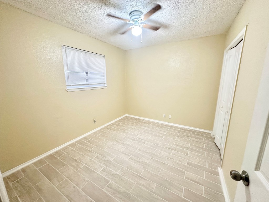 4302 Scottsdale Road, Unit B Austin, TX 78721 - Photo 31 of 37 Unfurnished bedroom featuring a closet, a textured ceiling, ceiling fan, and wood finish floors