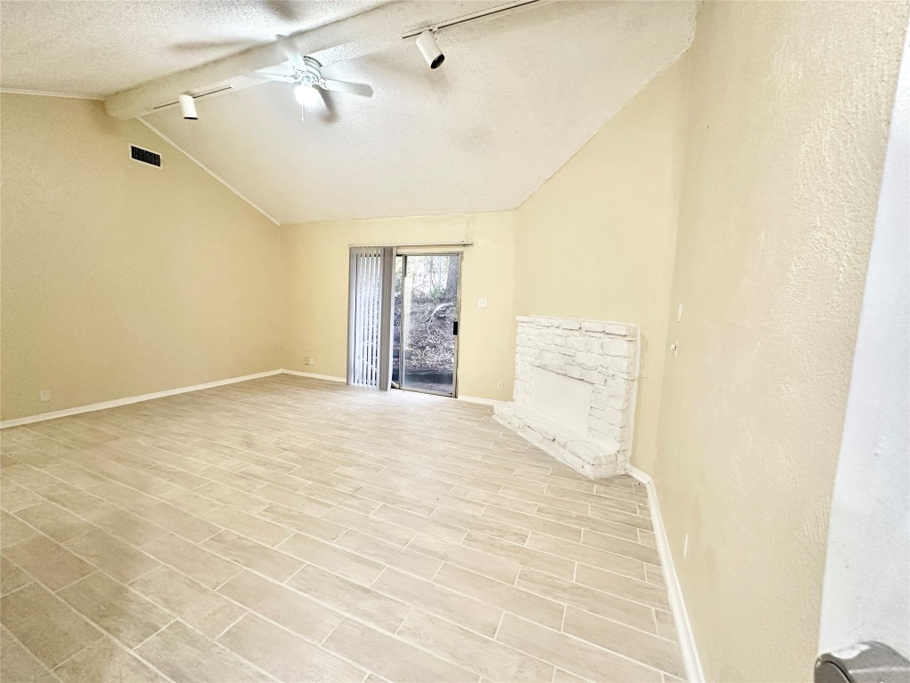 4302 Scottsdale Road, Unit B Austin, TX 78721 - Photo 5 of 37 Unfurnished room featuring track lighting, a textured ceiling, a fireplace, and a ceiling fan