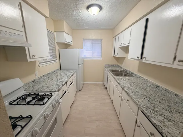 a kitchen with granite countertop white cabinets and white appliances