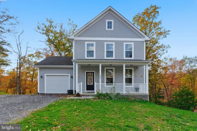 a view of a brick house with a large windows and a yard with plants and large trees