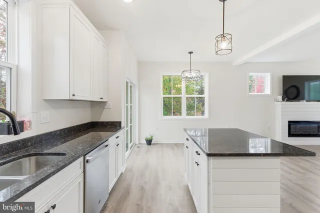 a kitchen with granite countertop a sink a counter top space cabinets and stainless steel appliances