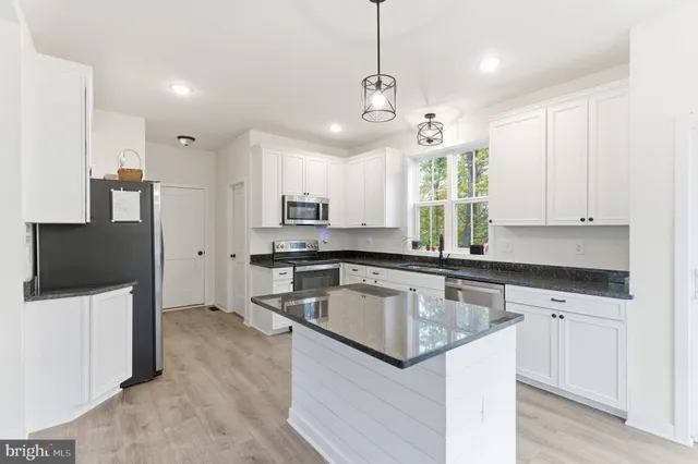 a kitchen with stainless steel appliances granite countertop a sink a stove and a refrigerator