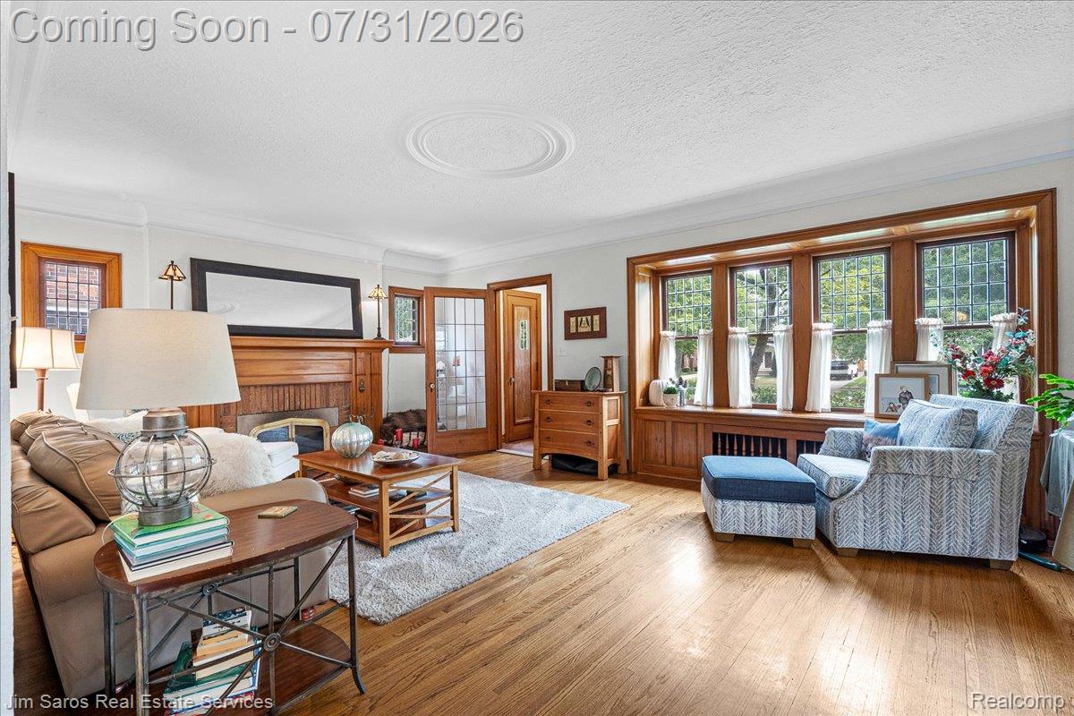 637 Washington Road Grosse Pointe, MI 48230 - Photo 17 of 40 Living area featuring wood-finish flooring, a fireplace with a wood mantel, and crown molding