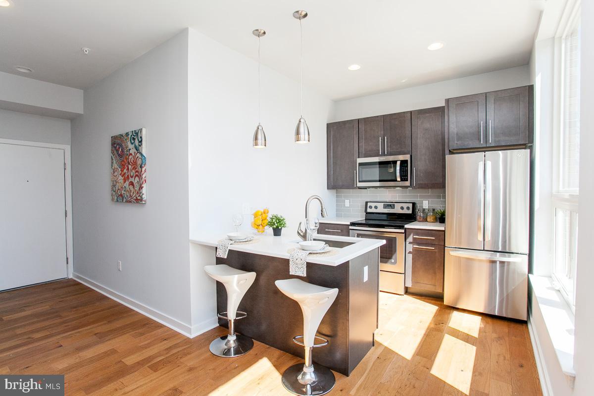 5938 Henry Avenue, Unit 12 Philadelphia, PA 19128 - Photo 8 of 19 a kitchen with stainless steel appliances a refrigerator stove microwave and cabinets