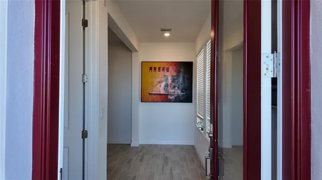 a view of a hallway with wooden floor and closet