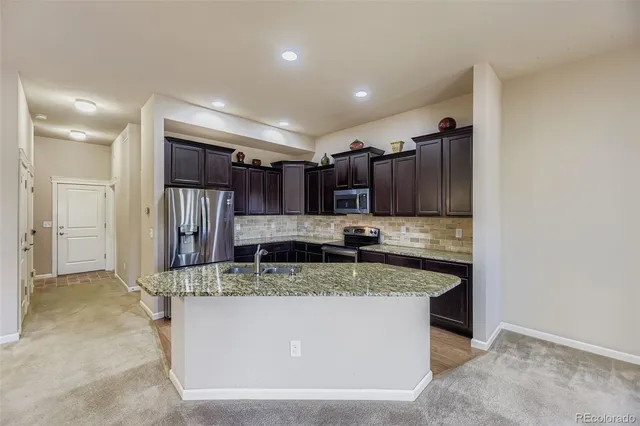 a kitchen with stainless steel appliances granite countertop a sink and a refrigerator