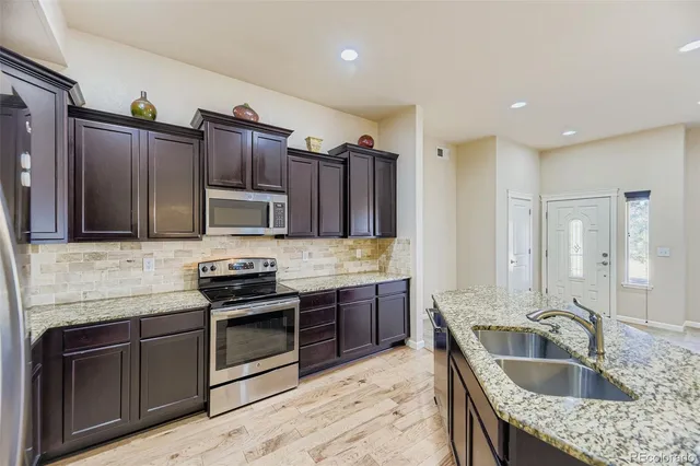 a kitchen with granite countertop a sink cabinets and stainless steel appliances
