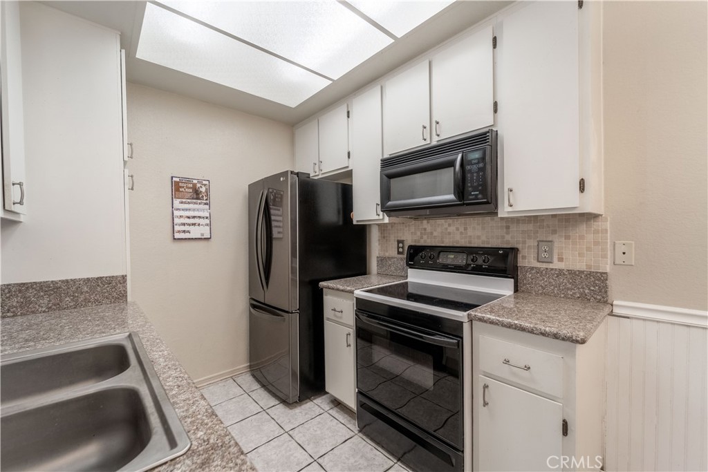 20702 El Toro Road, Unit 413 Lake Forest, CA 92630 - Photo 6 of 29 a kitchen with granite countertop a refrigerator stove and microwave
