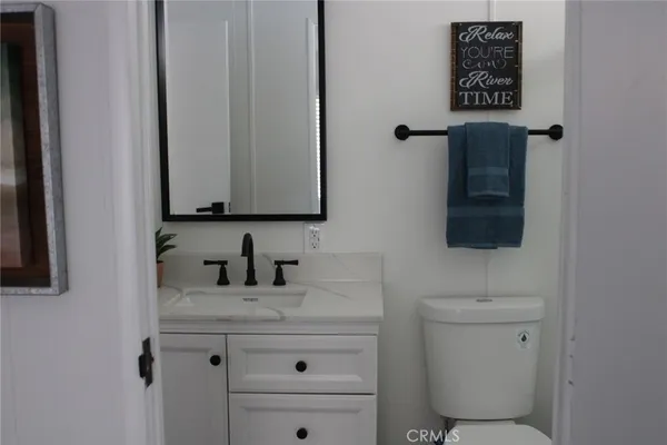 a bathroom with a toilet sink vanity and mirror