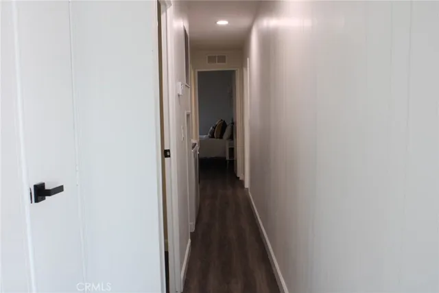 a view of a hallway with wooden floor and a bathroom
