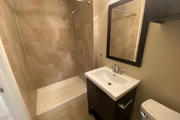 2402 Rio Grande Street, Unit 6 Austin, TX 78705 - Photo 3 of 3 A well-appointed bathroom features a tile shower and a contemporary vanity with a mirrored cabinet.