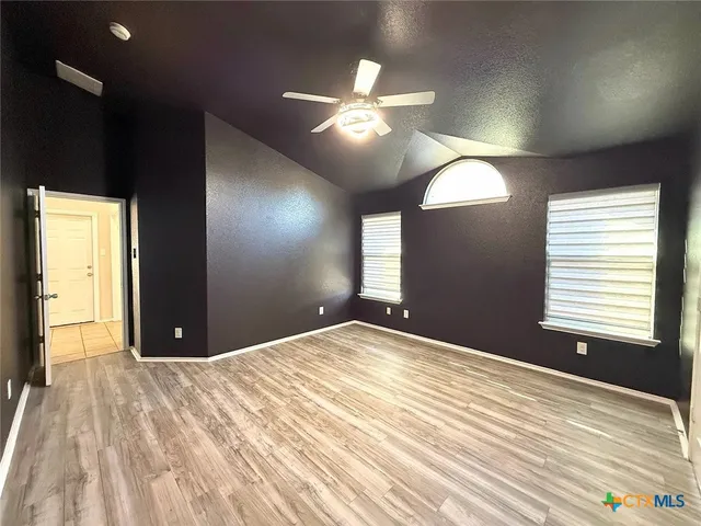 a view of an empty room with window and wooden floor
