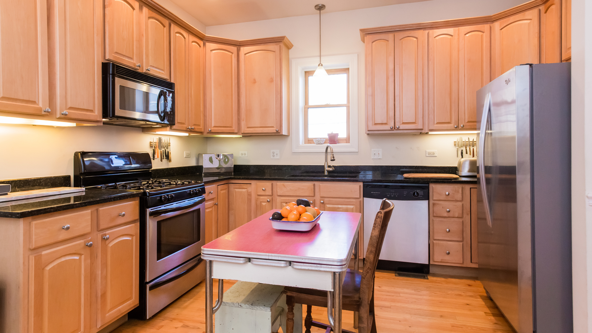 6963 North Sheridan Road, Unit 1E Chicago, IL 60626 - Photo 10 of 20 a kitchen with stainless steel appliances granite countertop a stove a refrigerator a sink a dining table and chairs with wooden floor