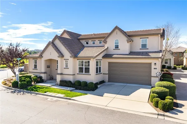 a view of a white house with a large windows and a yard with plants