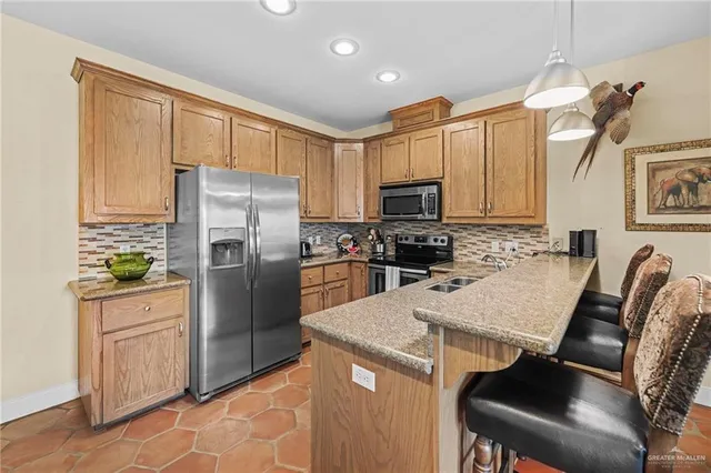 a kitchen with stainless steel appliances granite countertop a refrigerator a stove a sink a dining table and chairs with wooden floor