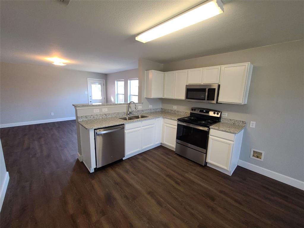 112 Ringneck Drive Sanger, TX 76266 - Photo 1 of 1 a kitchen with granite countertop white cabinets and white appliances