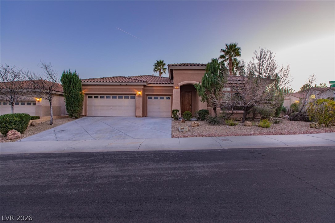 Mediterranean / spanish-style home with stucco siding, a tile roof, driveway, and a garage