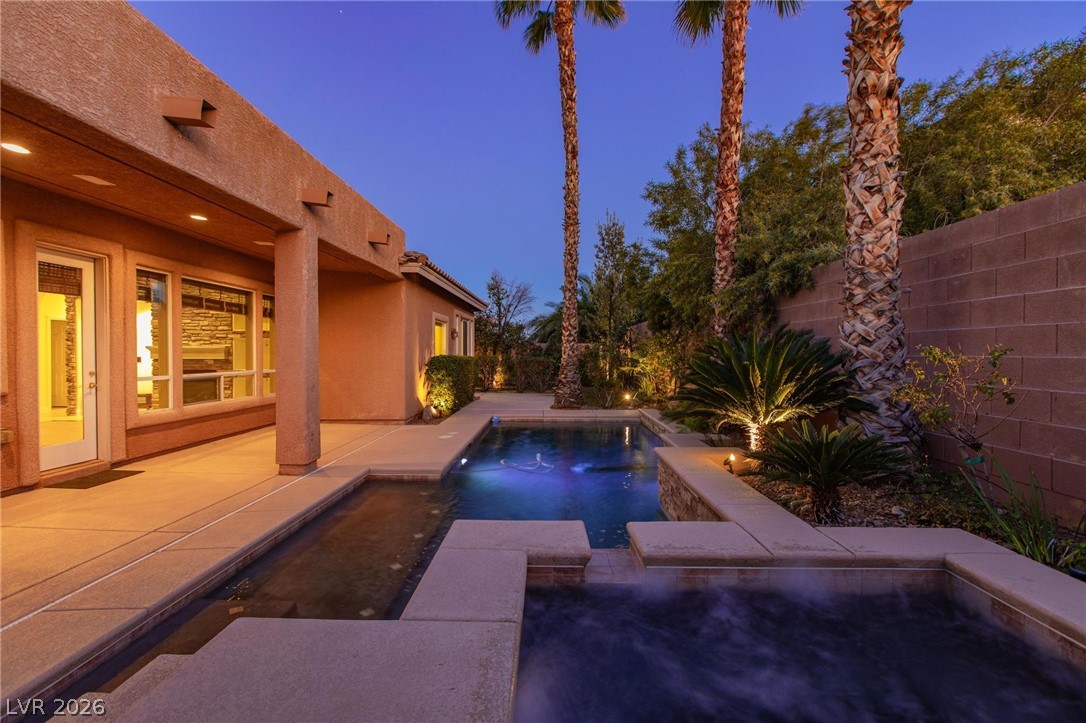 11425 Rancho Portena Avenue Las Vegas, NV 89138 - Photo 12 of 58 Pool at dusk with a patio area, a fenced backyard, and a pool with connected hot tub