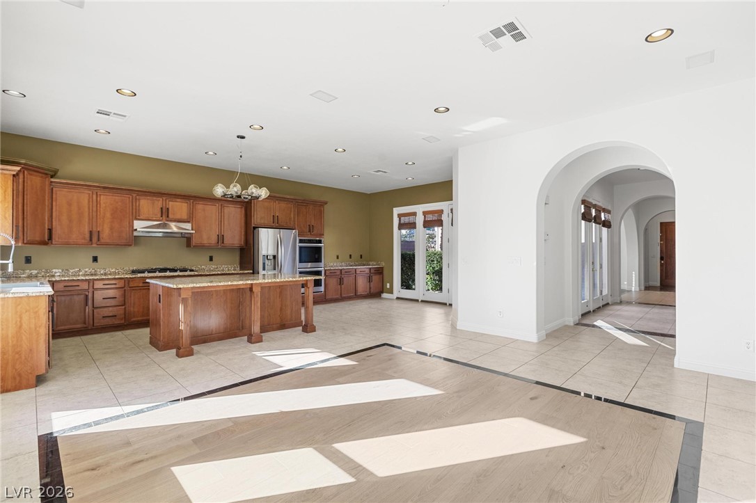 11425 Rancho Portena Avenue Las Vegas, NV 89138 - Photo 58 of 58 Kitchen featuring inlaid floor details, wood finish cabinets, light tile patterned floors, open floor plan, and arched walkways