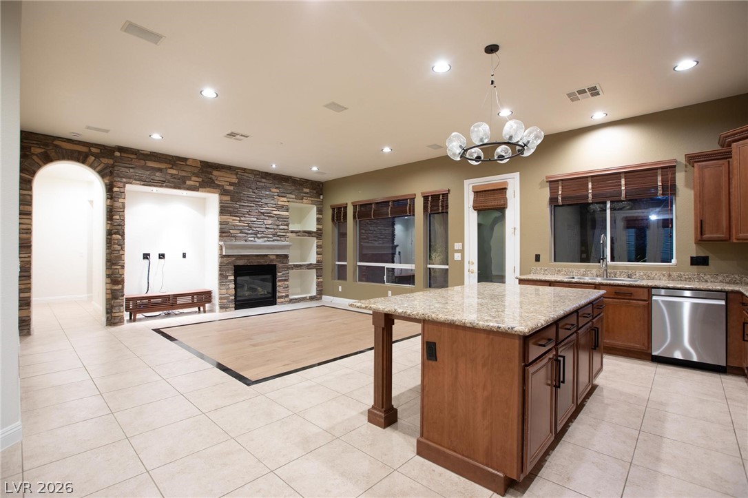 11425 Rancho Portena Avenue Las Vegas, NV 89138 - Photo 27 of 58 Kitchen with dishwasher, a kitchen island, a kitchen breakfast bar, light tile patterned floors, and light stone counters