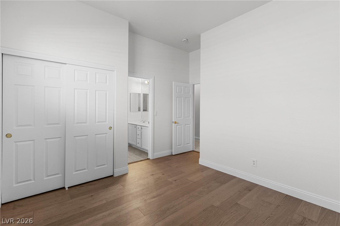 11425 Rancho Portena Avenue Las Vegas, NV 89138 - Photo 43 of 58 Unfurnished bedroom featuring connected bathroom, dark wood-style floors, a closet, and a high ceiling