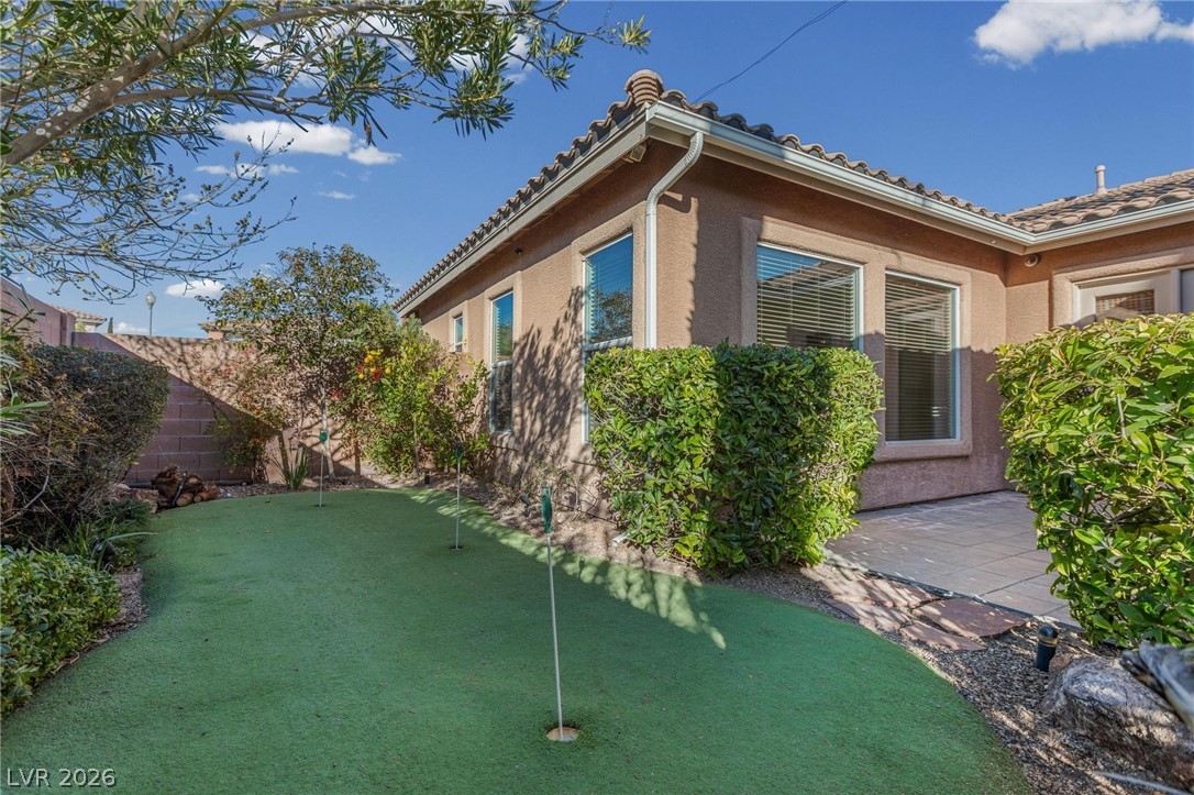 11425 Rancho Portena Avenue Las Vegas, NV 89138 - Photo 45 of 58 View of home's exterior featuring a fenced backyard, a putting green, stucco siding, and a patio area