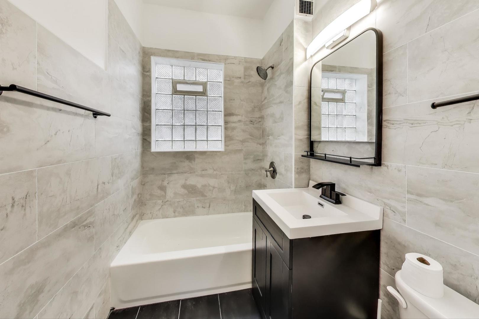 928 East 46th Street Chicago, IL 60653 - Photo 26 of 28 a bathroom with a sink mirror and a bathtub