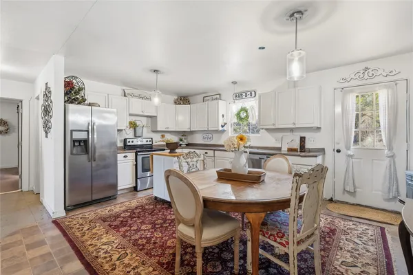 a kitchen with stainless steel appliances granite countertop a refrigerator a stove a sink dishwasher a dining table and chairs with wooden floor