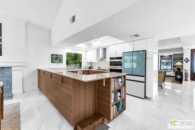 a large kitchen with stainless steel appliances a large counter top a stove a chimney a sink and a refrigerator